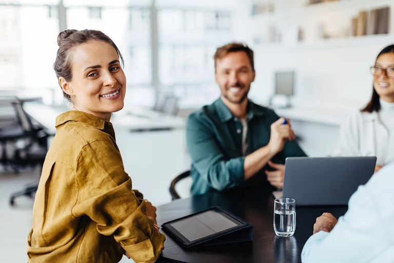 Foto: Gesco: Zwei Frauen und ein Mann sitzen in einem Konferenzraum vor einem Laptop und laecheln