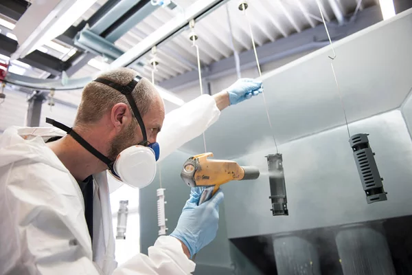 Foto: Gesco: Ein Mann in Schutzkleidung und Maske bearbeitet eine Maschine mit einem Foehn in einer Fabrik