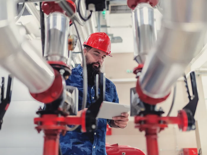 Foto: Gesco: Ein Mann in Schutzkleidung und Helm bedient eine Maschine mit grossen Metallrohren