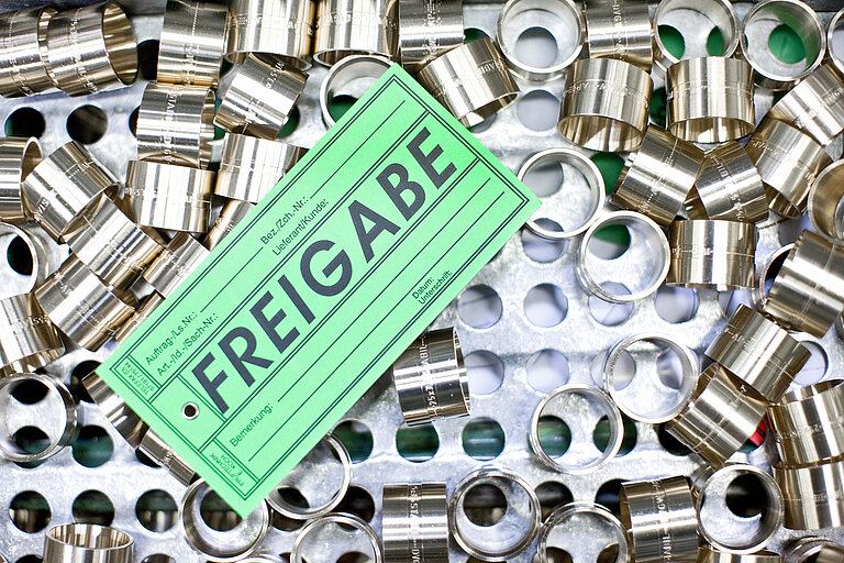 Foto: Gesco: Ansammlung von Metallteilen im Fertigungsprozess mit einen Ticket mit der Aufschrift: Freigabe