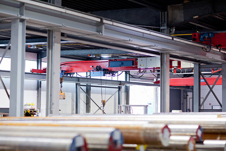 Foto: Gesco: Eine Produktionshalle mit Maschinen und gestapelten Metallrohren im Vordergrund