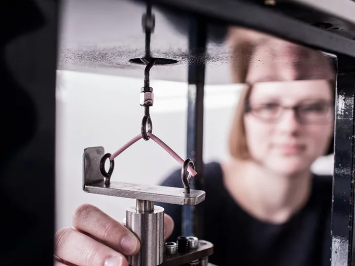 Foto: Gesco: Nahaufnahme einer Frau, sie steckt ein Metallstück in eine Maschine