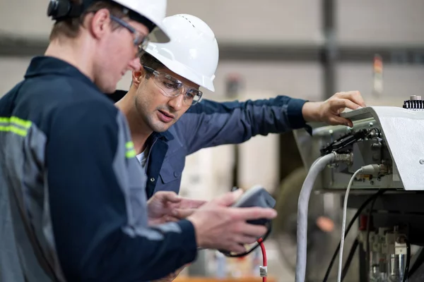 Foto: Gesco: Zwei Maenner in Schutzkleidung und Helmen bedienen eine grosse Maschine mit einem Geaet