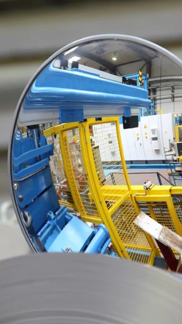 Foto: Gesco: Ein runder Spiegel reflektiert eine industrielle Halle mit gelben Metallgestellen