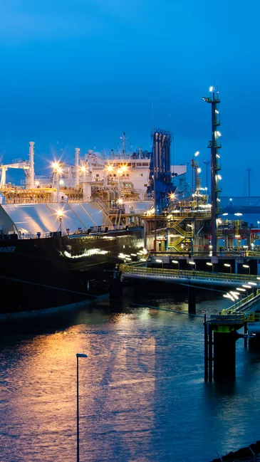 Foto: Gesco: Grosses Container Schiff beladen mit Containern, naechtliche Atmosphaere mit Lichtern