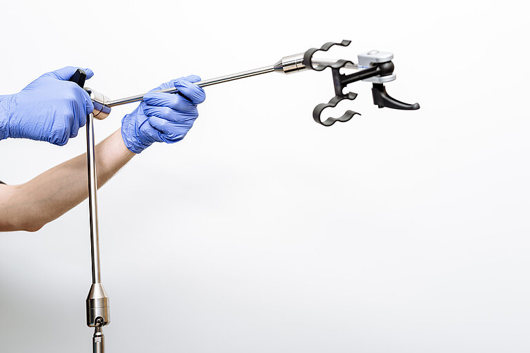 Foto: Gesco: Zwei Haende in blauen Handschuhen halten ein medizinisches Gerät mit langem Schaft